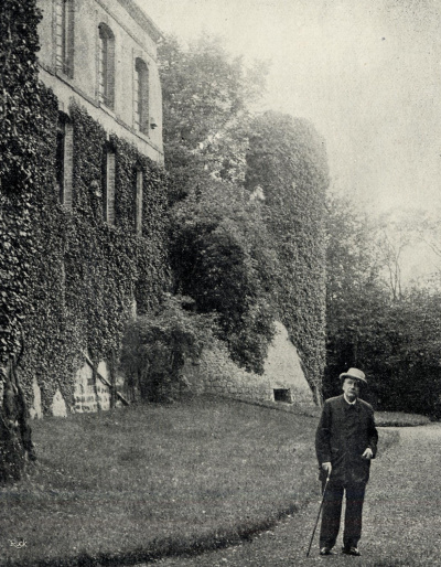 Jules Massenet debout devant sa maison, une canne à la maison.<br>
