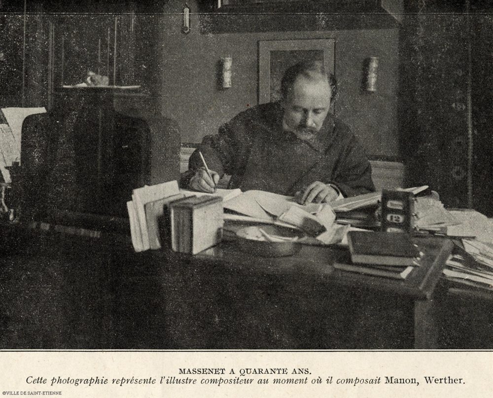Jules Massenet assis à une table de travail, un crayon en main.<br>